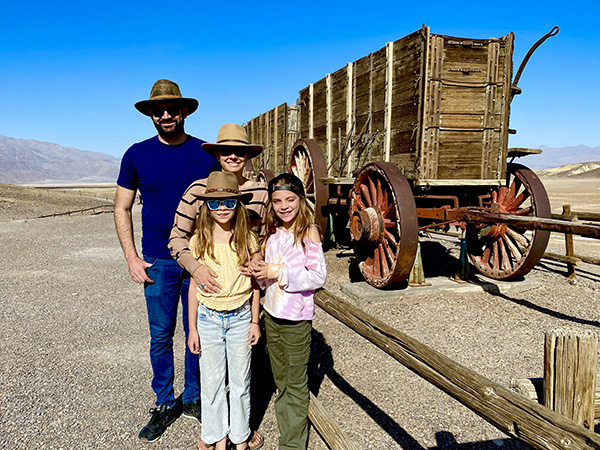 James Low, his wife, and two children stand in front of an historic 20 Mule Team wagon in Death Valley, California